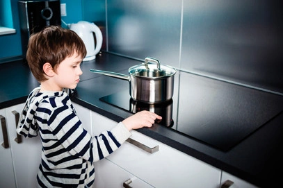 Cute 6 year old boy increases the power of heating under the pot on the induction stove