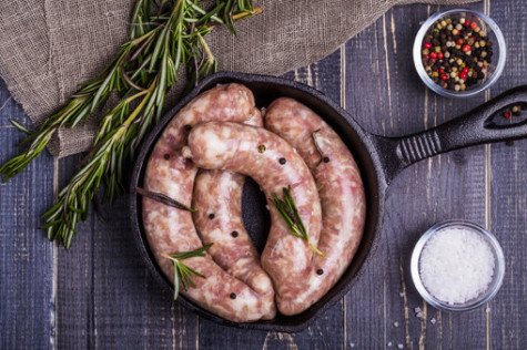 Raw sausage with spices on a dark wooden background