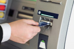 male hand businessman inserts credit card into the ATM and withdraws money