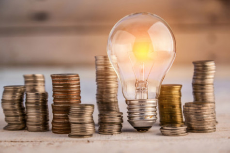 glowing light bulb among many coins heap business concept