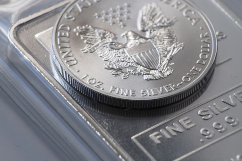 Silver Coin Bullion 1 ounce on top of a larger bullion bar, precious metal investments.